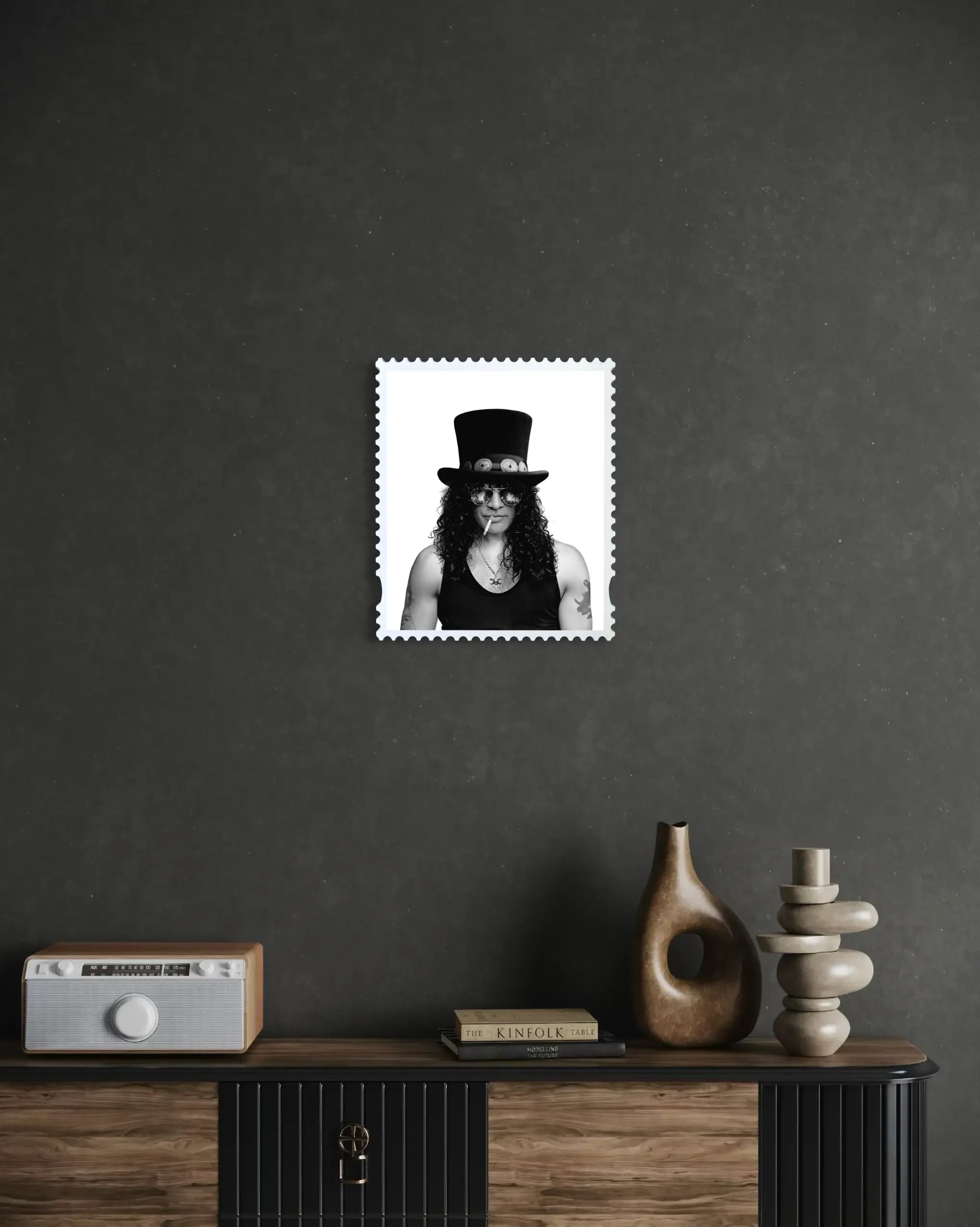 Slash Skin & Bones lenticular stamp artwork mounted on a dark textured wall above a wooden sideboard styled with ceramic vases, stacked stones and a vintage radio – portrait state shown. #size_medium