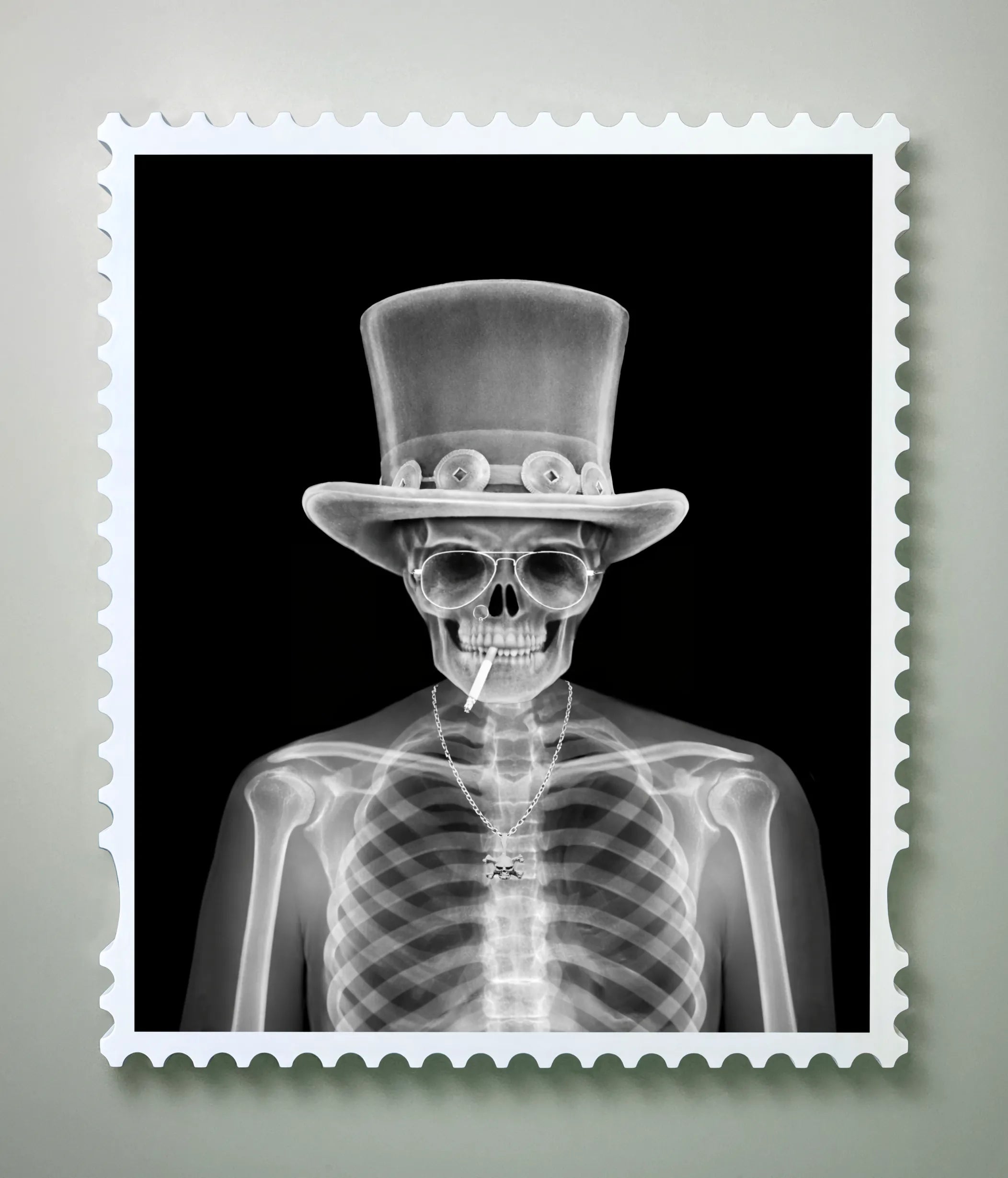 X-ray image of a skeleton in a top hat, aviator sunglasses and chain necklace, cigarette between the teeth, framed in a postage stamp border against a black background – the X-ray state of a lenticular artwork.
