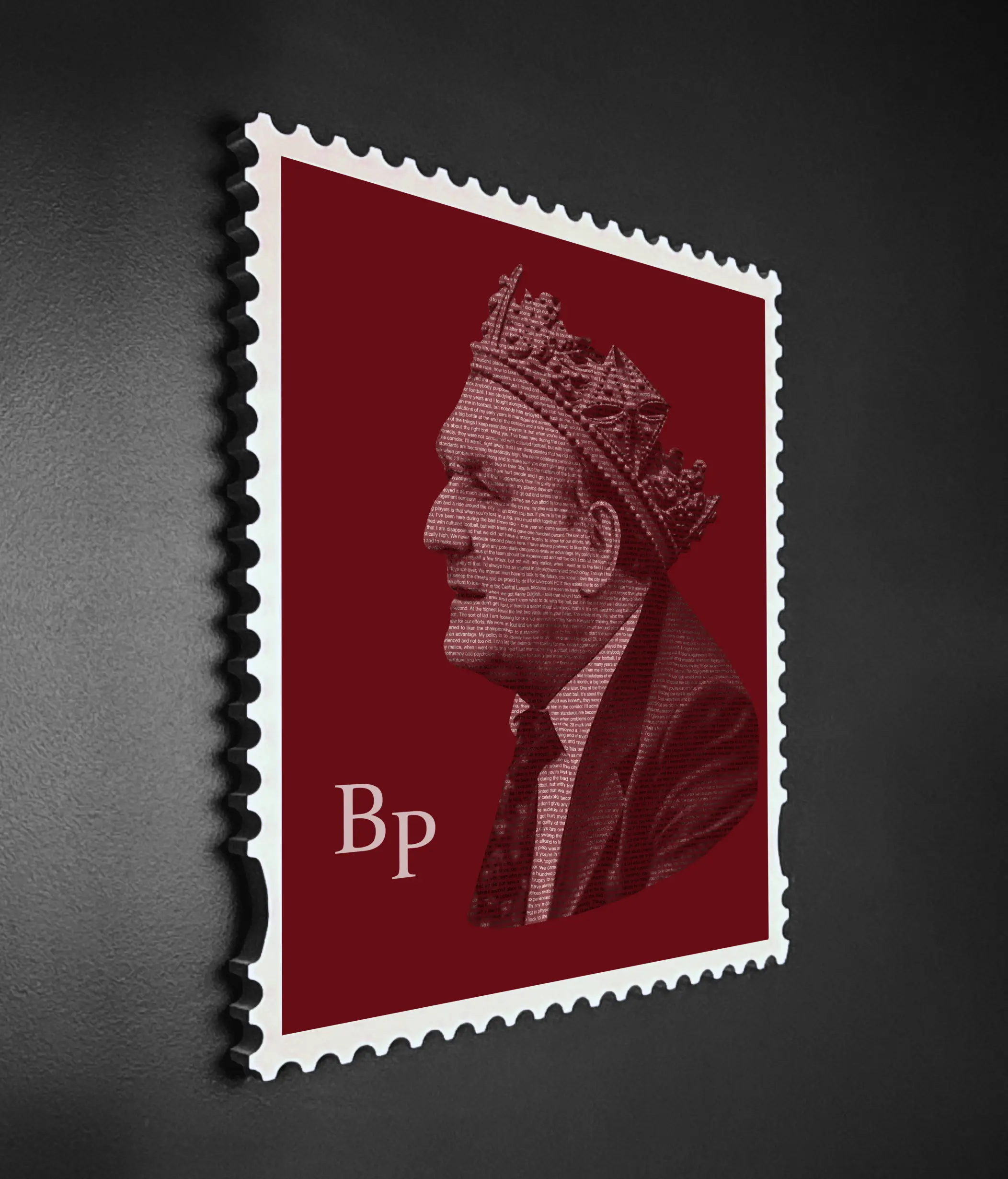 Angled close-up of the Bob Paisley framed stamp artwork in a handmade white wooden stamp frame against a dark background, showing the depth and three-dimensional quality of the premium aluminium dibond print, with his quotes forming the crowned portrait in layered crimson typography.
